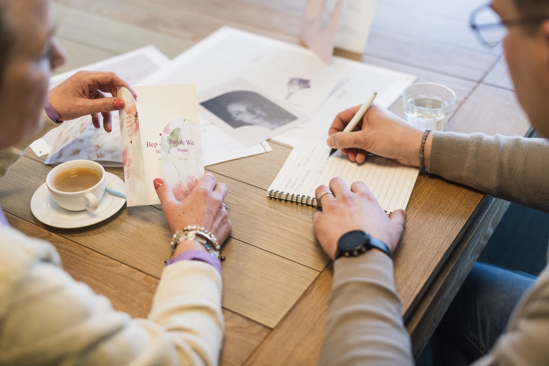 Handen bespreken rouwdrukwerk aan tafel