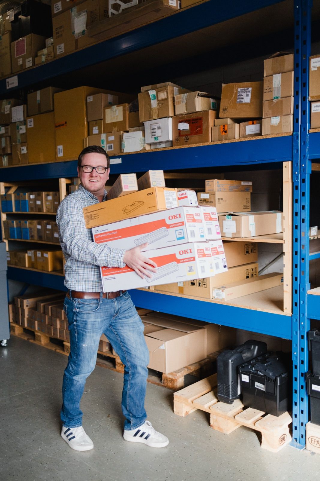 Medewerker in magazijn met OKI-dozen